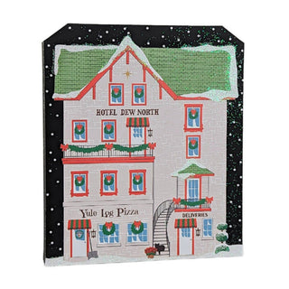 3/4" thick wooden replica with an illustration of a Christmas-themed building with 'Hotel Dew North' and 'Yule Log Pizza' text, decorated with wreaths and snow.