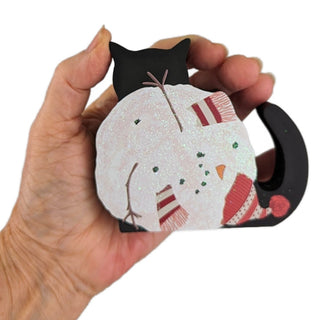 3/4" thick wooden replica with an illustration of a black cat with a snowman all balled up