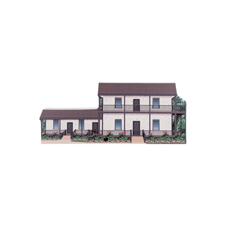 3/4" wooden replica with an illustration of a two story house with white brick and brown roof with landscaping 