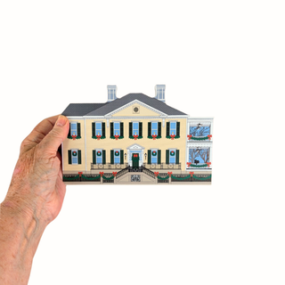 Hand holding a miniature 3/4" thick wooden model of a house against a white background
