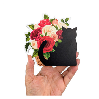 Hand holding a black cat-shaped 3/4" thick wooden cutout with floral design on a white background