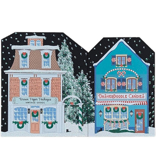 Two colorful Christmas-themed buildings with decorative elements on a snowy background.