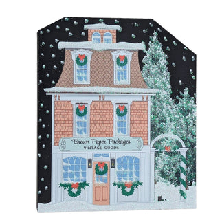 3/4" thick wooden replica with an illustration of a Christmas-themed store front with wreaths and snowflakes on a black background