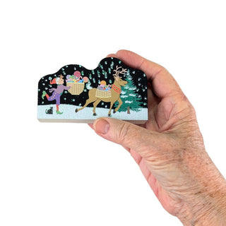 Hand holding a wooden repica  with a reindeer and Christmas scene design.