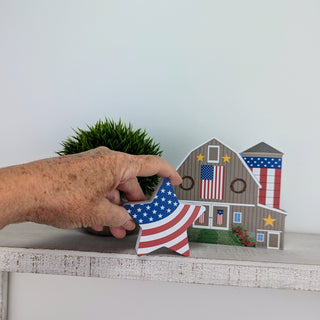 3/4" thick wooden american flag cut into a star shape with a patriotic barn on a shelf