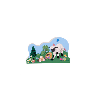 3/4" thick wooden replica with an illustration of a lamb, Easter eggs, and flowers on a grassy field with trees and a blue sky.