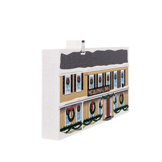 Decorative wooden replica of a building facade with wreaths and 'Colonial Inn' sign.
