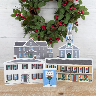 Set of Christmas-themed paper buildings with a wreath in the background