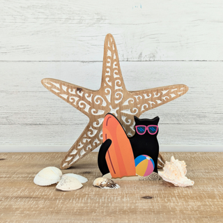 Decorative scene with a starfish, cat, and beach ball on a wooden surface.