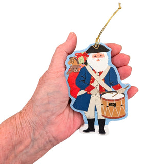 Hand holding a Christmas ornament with a soldier and drum design.