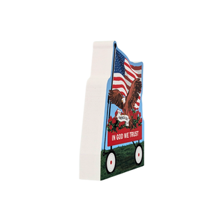 A small decorative wooden sign shaped like a wagon, featuring an American flag, an eagle, red flowers, and the words 'IN GOD WE TRUST' on a plain white background.