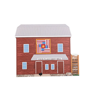 3/4" thick wooden illustration of a model of a red mill with a flag quilt design above the entrance labeled 'Four Flags Grist Mill'.