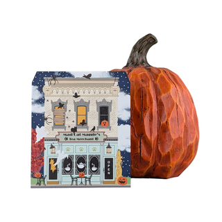A Halloween-themed tea merchant gift shelf sitter displayed next to a carved decorative orange pumpkin on a plain white background. The wooden shelf sitter illustrated storefront with bats, pumpkins, and the text 'Misty Elf Margaret's Tea Merchant'.