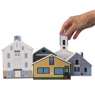 Set of miniature model houses with a hand holding one of them on a white background