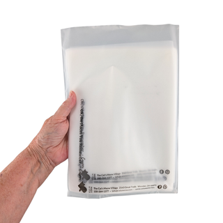 Hand holding a clear plastic bag with text on a white background