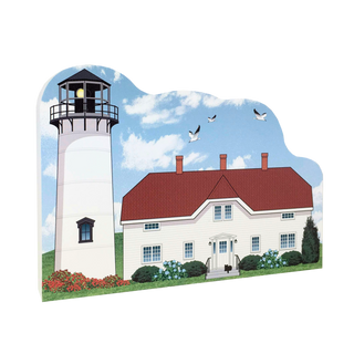 wooden replica with a design of a Lighthouse and house with birds flying against a blue sky