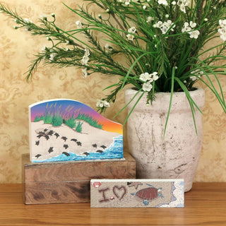 Decorative items including a vase with greenery, a small painting, and a wooden block with 'I love' text on a wooden surface.