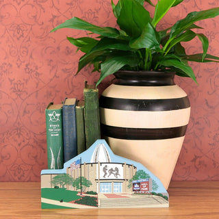 Decorative vase with striped design on a wooden surface against a red patterned wall.