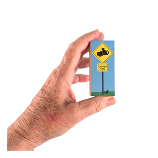 hand holding wood block with a caution black cats crossing sign