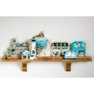 Set of decorative boxes with coastal designs on a wooden shelf against a white background