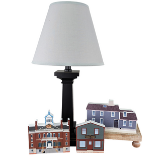 Table lamp with a white shade and decorative models of houses on a white background