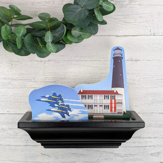 Decorative piece with a lighthouse and airplane design on a wooden surface.