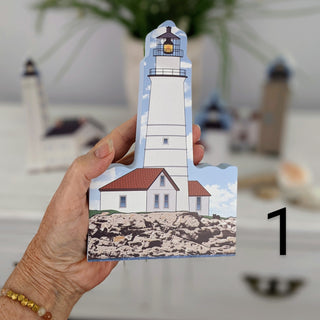hand holding wooden replica of the Boston harbor Lighthouse