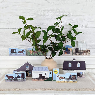 Wooden 3/4" Replica Decorative items including a potted plant, small model houses, and horse-drawn carriage pictures on a shelf.