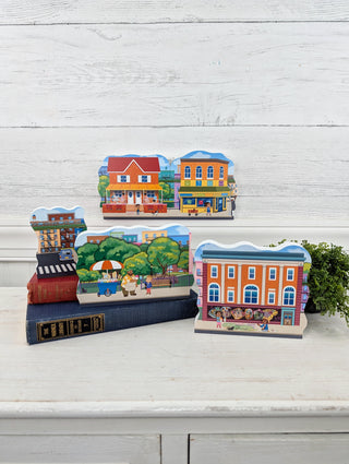 Set of colorful 3/4" thick wooden building models on a white surface with a light wooden background