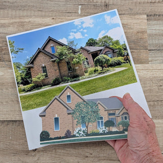 Hand holding a card with a printed house design on a wooden surface