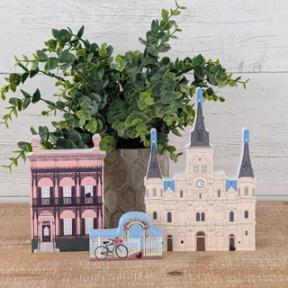 Decorative vase with plant on a wooden surface, featuring architectural designs.