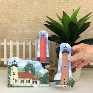 Set of three lighthouse cards held by a hand with a plant in the background