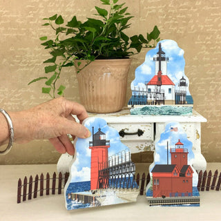 Decorative lighthouse cutouts on a table with a plant in the background