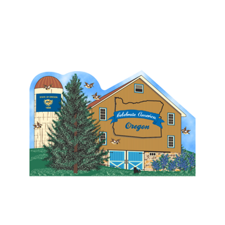 3/4" thick wooden cutout of a barn with 'Celebrate America Oregon' text, surrounded by trees and a blue sky.