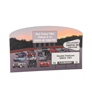 wooden replica of a drive-in theater with cars and a sign, set against a scenic sunset background.