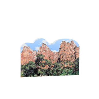 3/4" wooden replica with an illustration of a scenic view of red rock formations and green trees on a white background