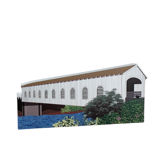3/4" thick wooden cutout of a covered bridge with a brown roof and white walls, surrounded by greenery and water.