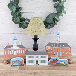 Decorative lamp with small 3/4" thick wooden model buildings and a wreath on a wooden surface.