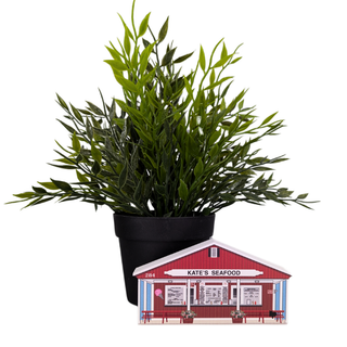 Potted plant next to a miniature model of Kate's Seafood restaurant on a white background