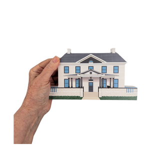 Hand holding a 3/4" thick wooden illustration of a house on a white background