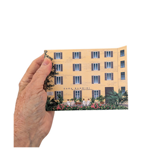Hand holding a 3/4" thick wooden replica with an illustration of a building and people on a white background