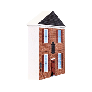 A miniature brick house model with a white facade, dark gray shingled roof, and detailed windows, shown on a plain white background.