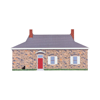 3/4" thick wooden replica with an illustration of a small stone house with a gray roof, red front door, white shutters, two chimneys, green grass, and a black cat on the lawn, shown on a plain white background.