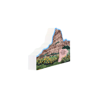 3/4" thick wooden replica with an illustration of a mountain landscape, with a rocky cliff, blue outline, green grass, yellow flowers, and a pink sign reading 'Western Slope' on a white background.