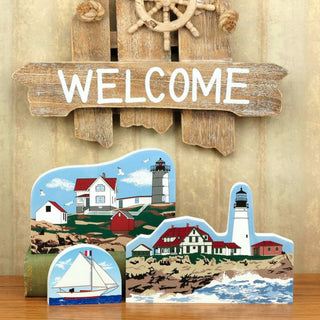 Decorative wooden sign with 'WELCOME' and nautical-themed magnets on a wooden surface.