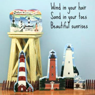 Decorative lighthouse models on a stand with a quote about Outer Banks on a blue background.