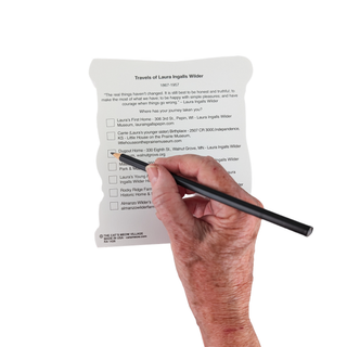 Hand holding a pen pointing to text on a 3/4" thick wooden  map of Laura Ingalls travels map