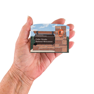 Hand holding a card with Cedar Breaks National Monument design on a white background