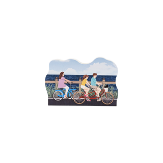 3/4" wooden replica with an illustration of  Three people riding bicycles on a scenic boardwalk with ocean view
