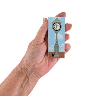 Hand holding a small wooden replica with a clock design against a white background